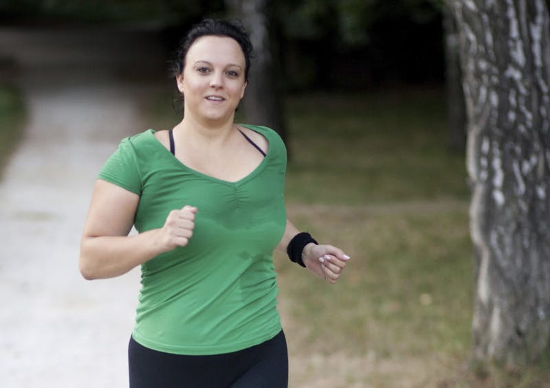 Overweight woman jogging in a park / forrest