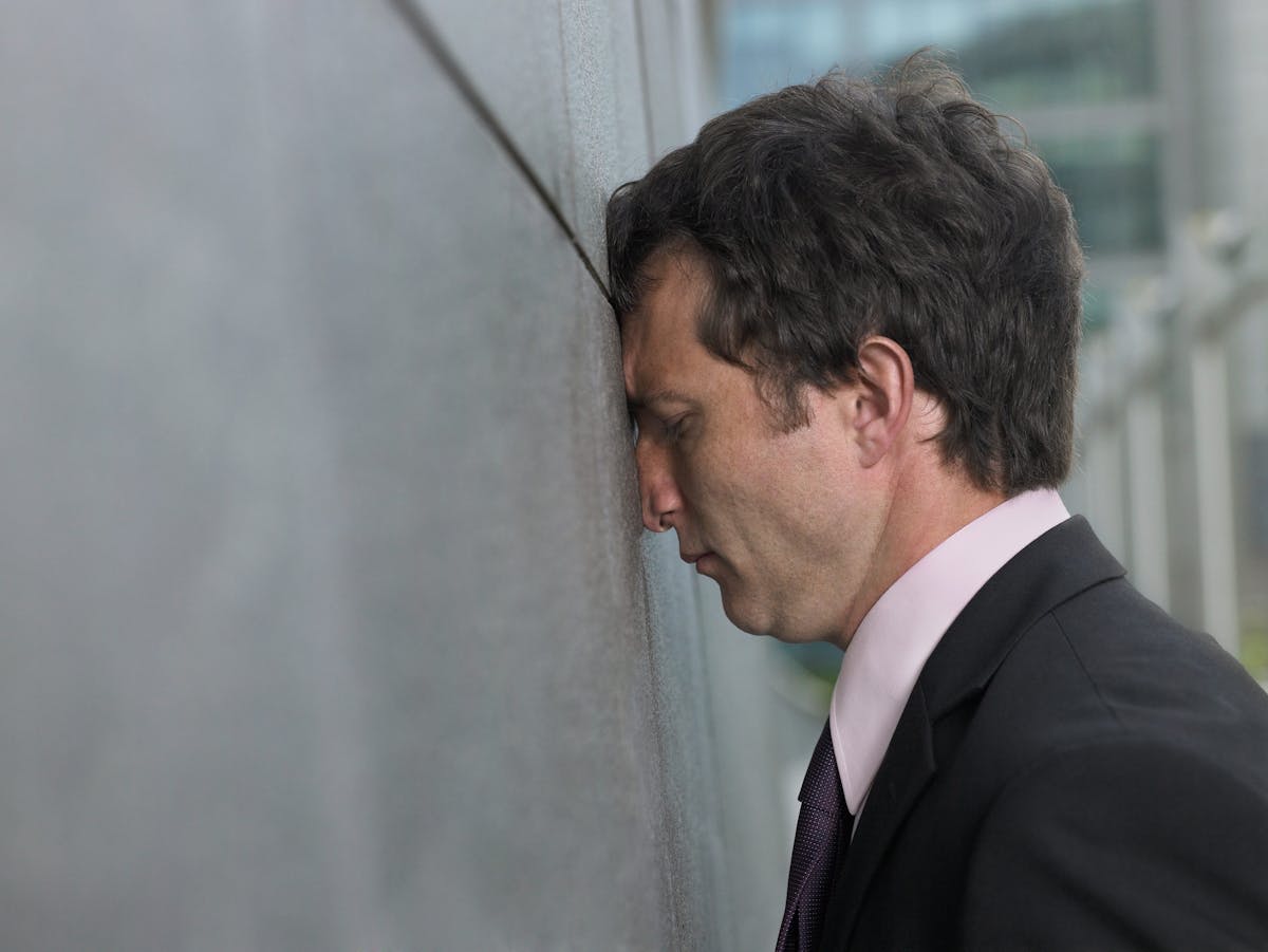 Businessman with face pressed against wall, profile, close-up