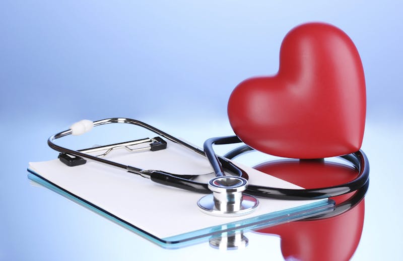 Medical stethoscope with clipboard and heart on blue background
