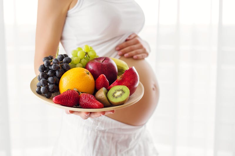 Pregnant woman holding fruit plate
