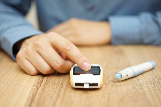 man testing glucose level with a digital glucometer, diabetes treatment
