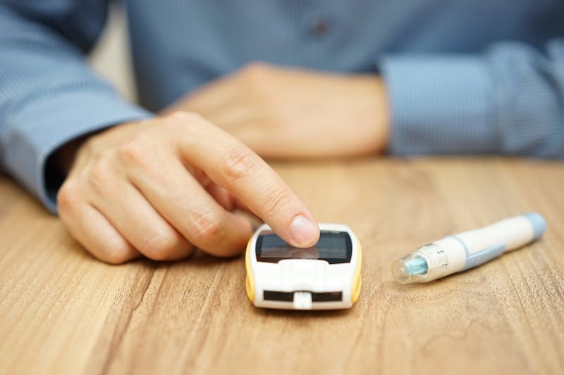 man testing glucose level with a digital glucometer, diabetes treatment