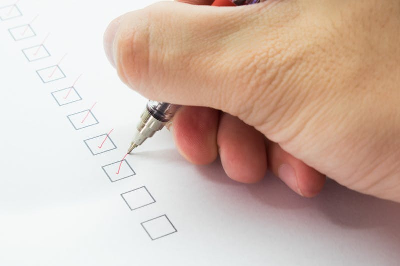 man is checking on list with red pen