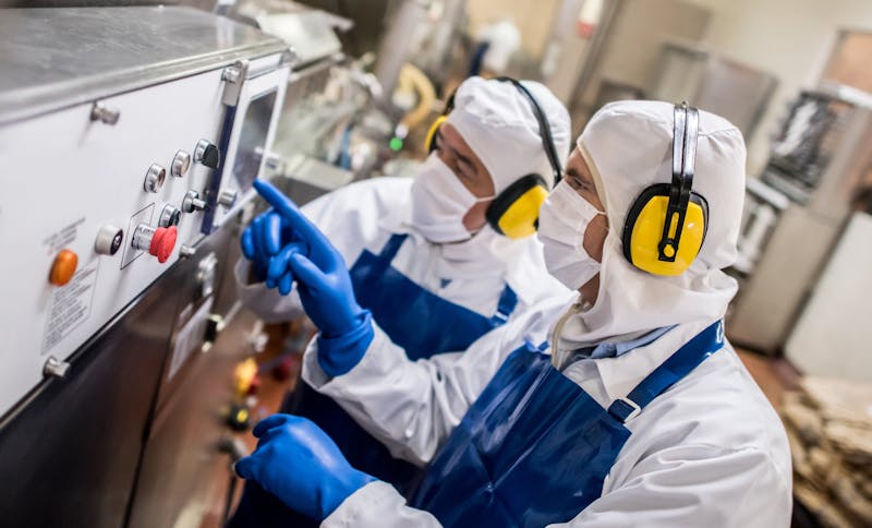Men operating machine at a food factory