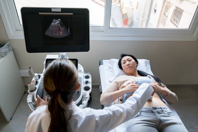 Asian woman lying down while female doctor is doing an ultrasound on her stomach