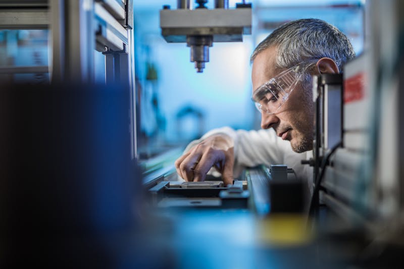 Quality control worker analyzing scientific experiment on a manufacturing machine.