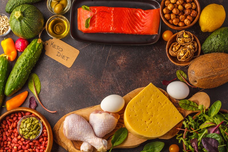 Keto (ketogenic) diet concept. High protein food, food frame background. Vegetables, fish, meat, cheese, nuts on a dark background.