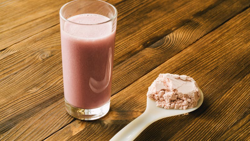Sports protein on the spoon and in a glass Cup