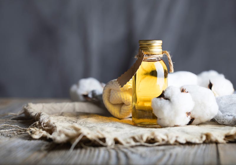 Cottonseed oil in a glass bottle on a wooden surface. Closeup