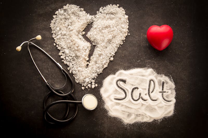 Sprinkled salt on dark background with broken heart shape made from salt.