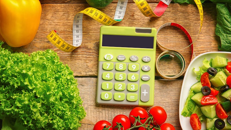 Calculator, measuring tape and set of healthy food on wooden table