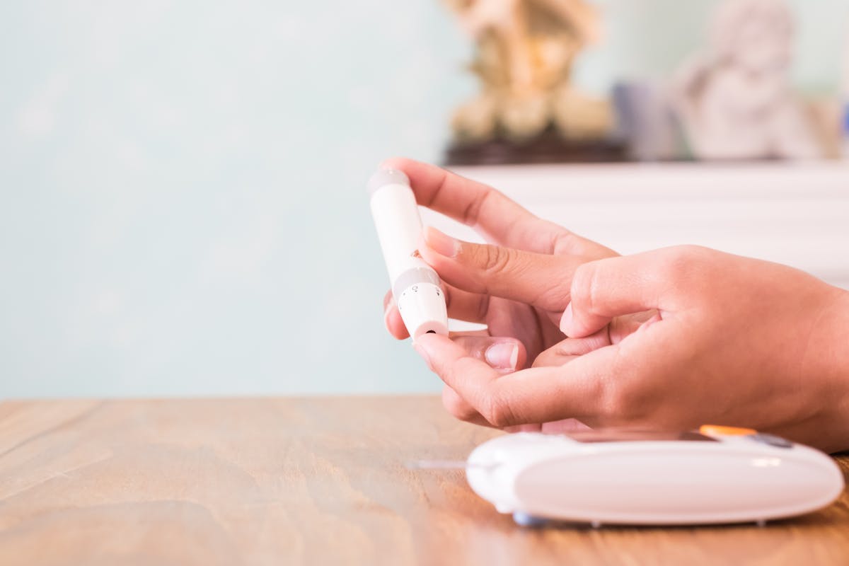 Close up of asian woman hands using lancet on finger to check blood sugar level by glucose meter, Healthcare medical and check up, diabetes, glycemia, and people concept