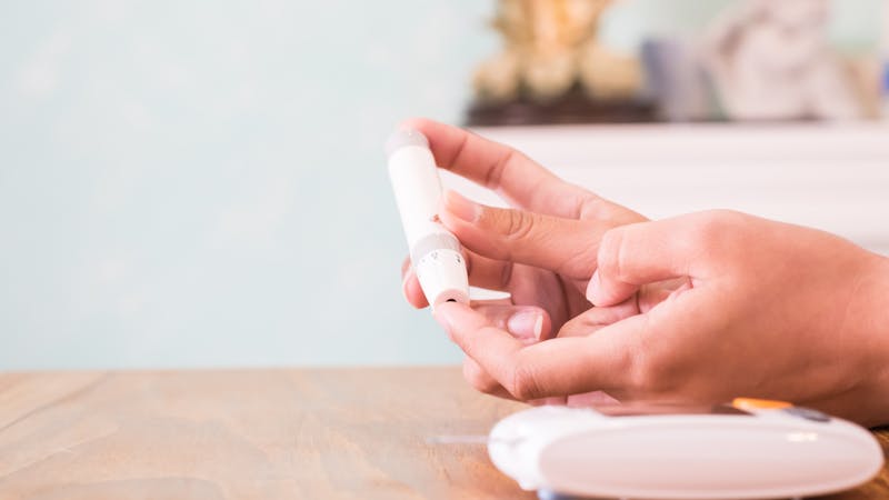 Close up of asian woman hands using lancet on finger to check blood sugar level by glucose meter, Healthcare medical and check up, diabetes, glycemia, and people concept