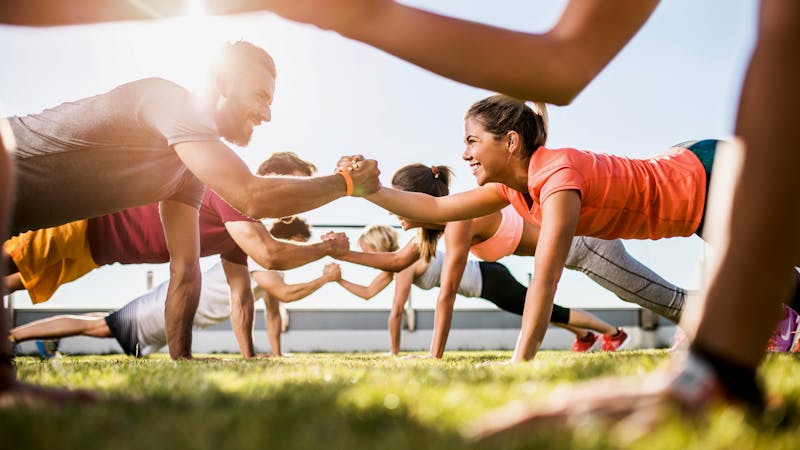 Happy athletic people cooperating while exercising on a sports training.