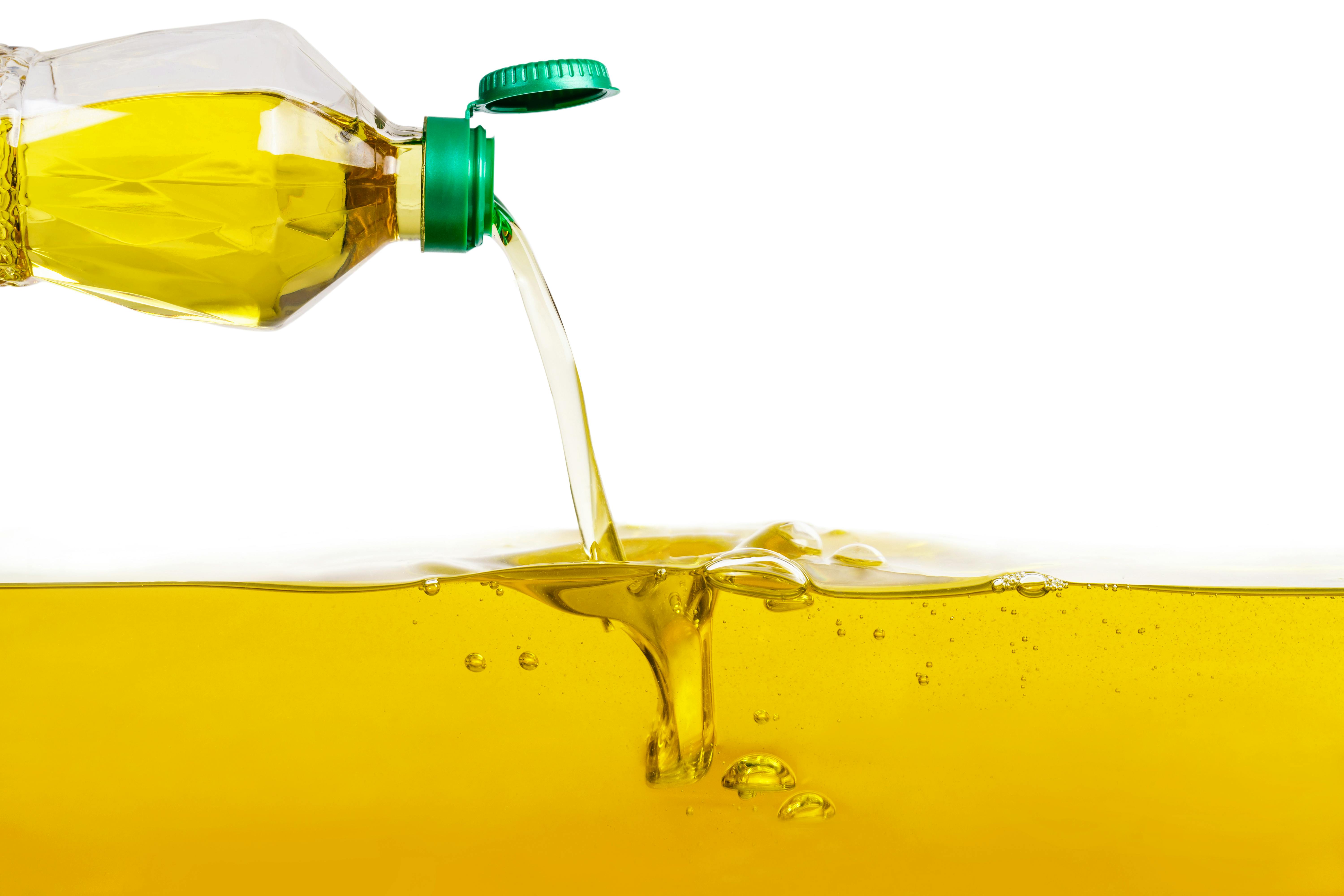 Vegetabilisk olja som hälls ut på vegetabilisk oljebakgrund