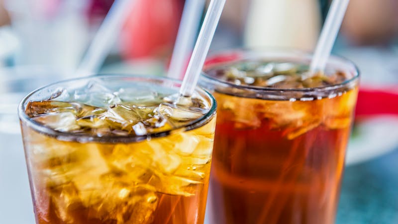 Macro closeup soda with ice cubes and straw in glass