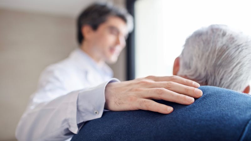 Doctor keeping hand on senior man's back