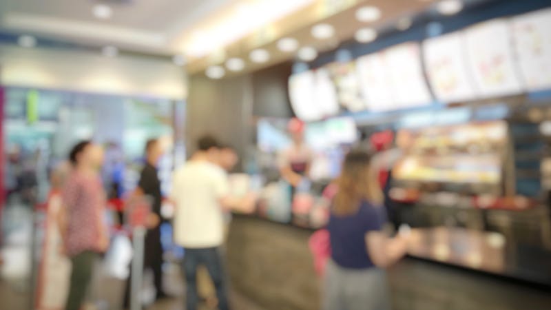 blurred abstract image of people standing for wait to order some food and make payment in fast food restaurant. Use as background image. vintage tone color and light effect.