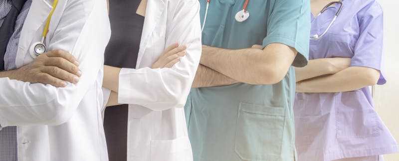 Doctors and nurses with uniform and stethoscope coordinate hands.
