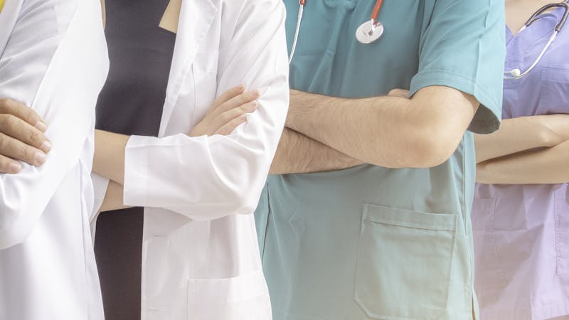 Doctors and nurses with uniform and stethoscope coordinate hands.
