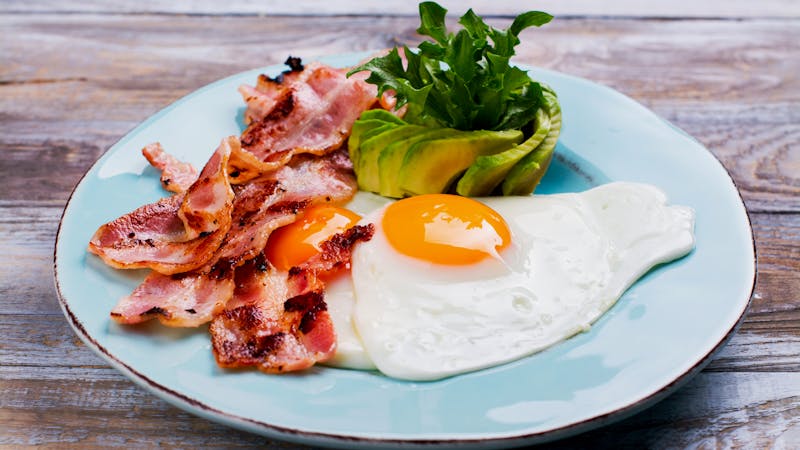 Continental breakfast with fried eggs, bacon and avokado