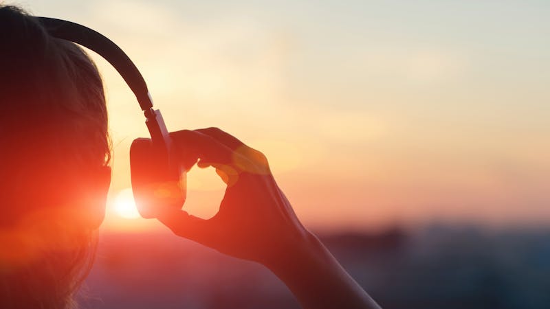Girl with headphones in the sunrise