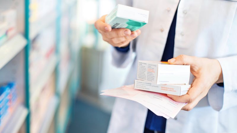 Pharmacist’s hands taking medicines from shelf