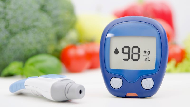 Glucometer and lancelet on vegetables background