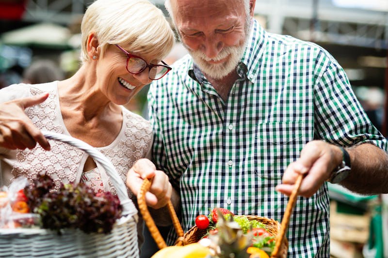 Portrait of beautiful elderly couple in market buing food