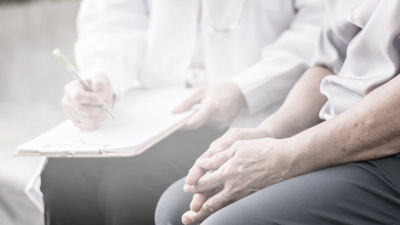 Parkinson and alzheimer female senior elderly patient with caregiver in hospice care. Old woman holding hand with doctor physician.