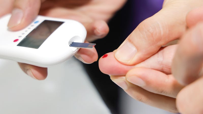 Close up of Doctor taking sample of diabetic patient’s blood using lancet pen,Healthcare and Medical concept