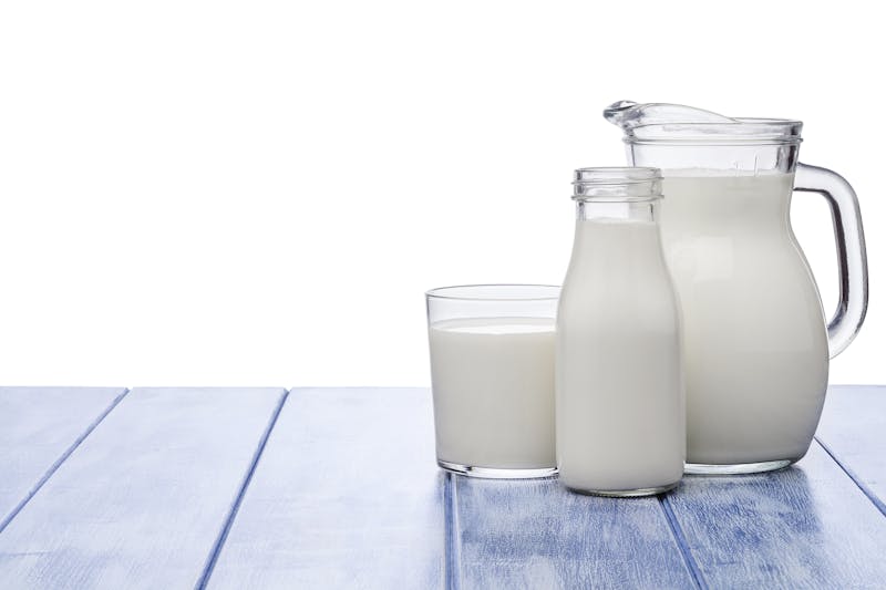 Milk jar, milk bottle and milk glass shot on blue striped table against blue striped table