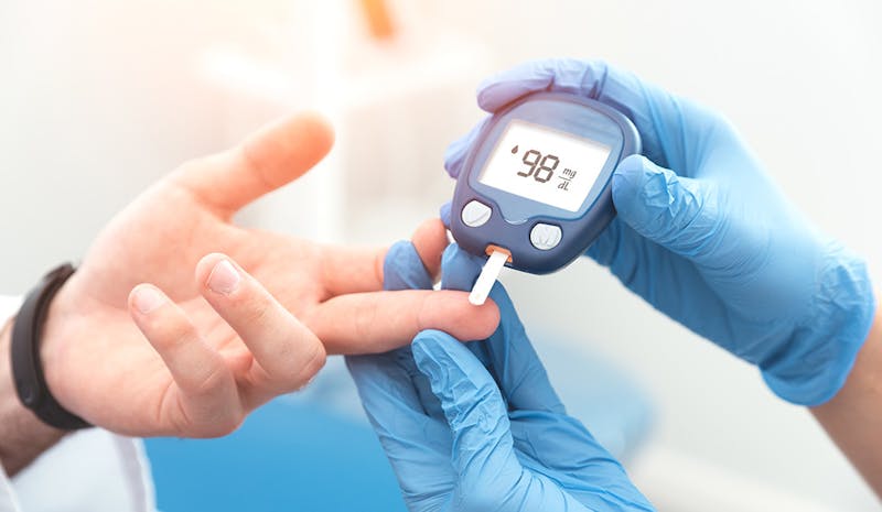 Doctor checking blood sugar level with glucometer