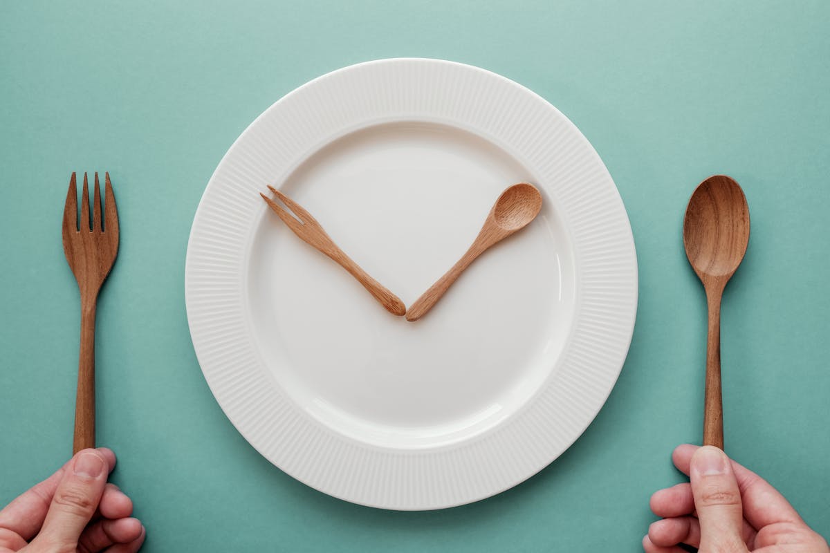 木勺和叉子像时钟一样放在白盘子上，间歇性禁食概念，生酮饮食，减肥，不吃饭新利18luck返利