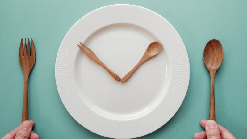 木勺和叉子像时钟一样放在白盘子上，间歇性禁食概念，生酮饮食，减肥，不吃饭新利18luck返利