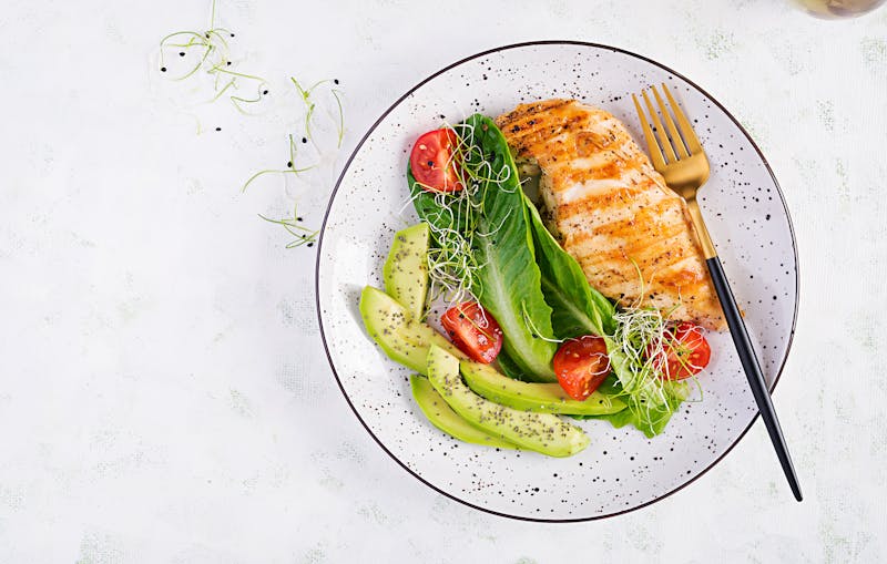 Chicken grilled fillet with salad fresh tomatoes and avocado. Healthy food, ketogenic diet, diet lunch concept. Keto/Paleo diet menu. Top view, flat lay