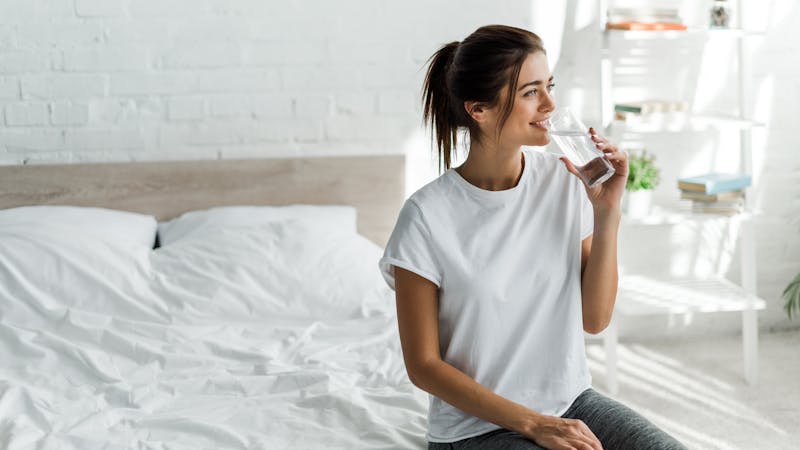 beautiful happy girl holding drinking water from glass in the morning