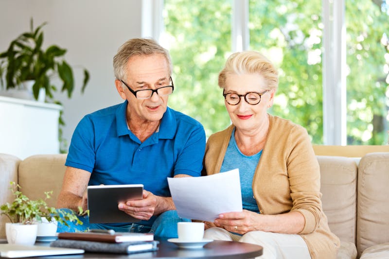 Retired couple watching bills and calculating monthly expenses