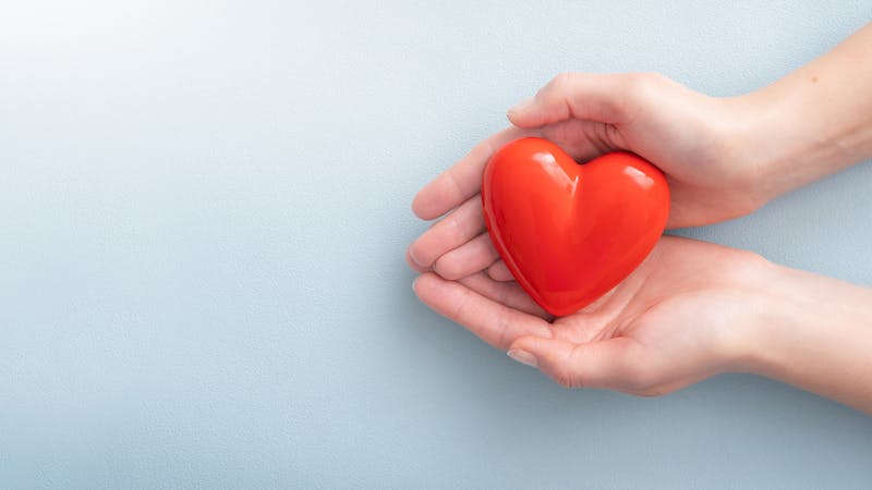 The woman is holding a red heart.