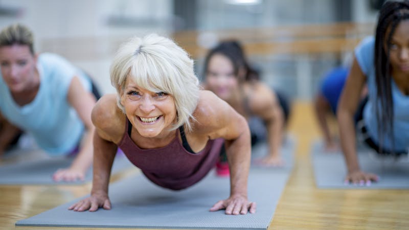 Senior Woman in Fitness Class in a Plank Pose Smiling stock photo