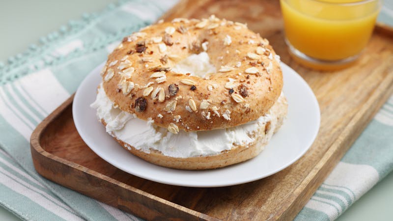 Breakfast with soft cheese bagel sandwich and a cup of orange juice