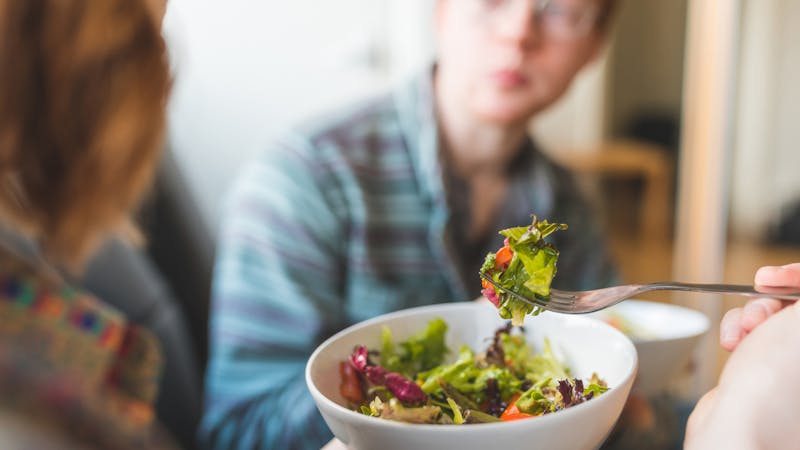 Couple eating healty salad at home on the sofa