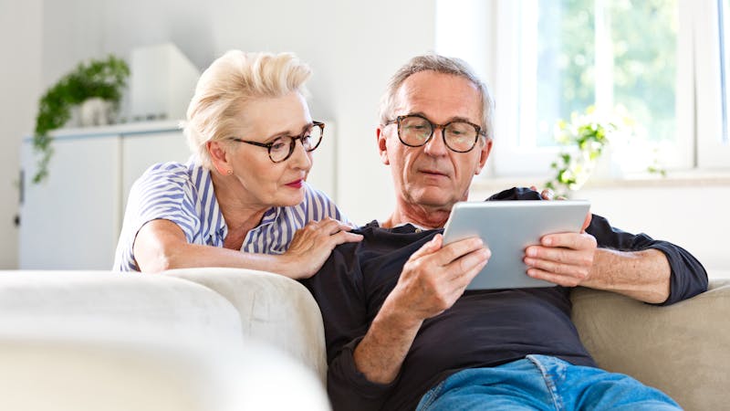 Senior couple watching digital tablet together at home