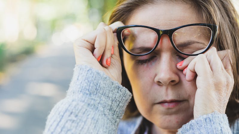 Woman rubbing her eye outdoors