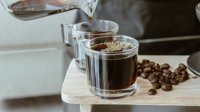 Cropped shot of Barista pouring a hot coffee after drip in a glass cup of coffee.