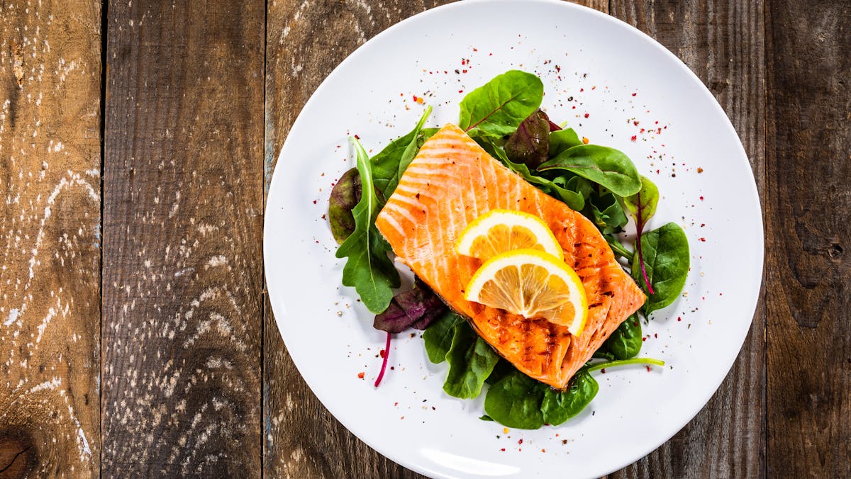 Grilled salmon on fresh vegetables on wooden table