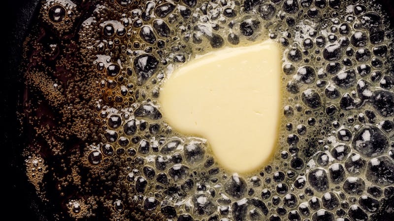 Fried butter, a piece of butter in the shape of hearts, fried on a black cast-iron pan.