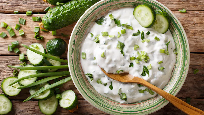 sauce of yogurt with herbs, spices and cucumber close-up on the table. raita. Horizontal top view